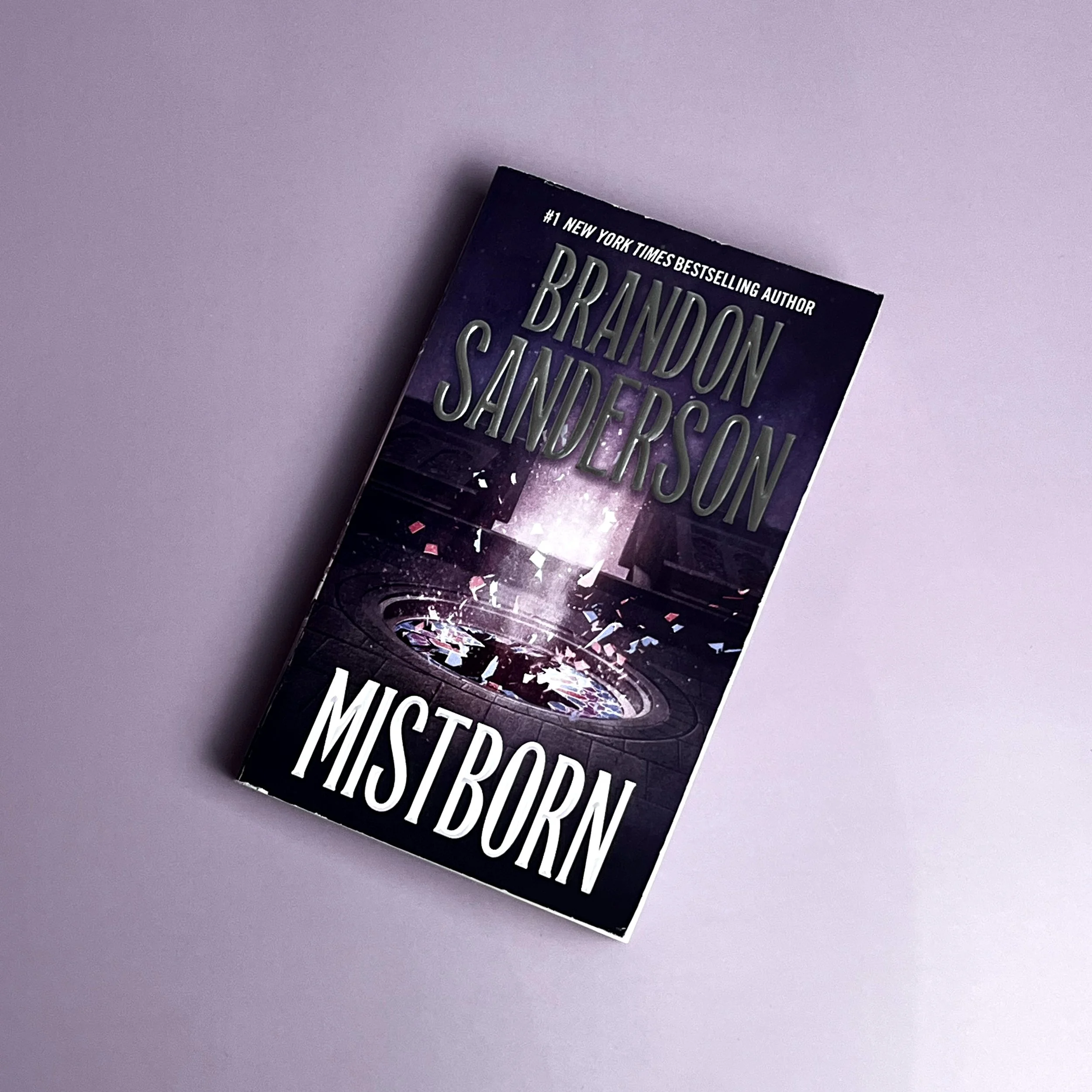 Standard paperback with semi-glossy finish. Dark background with light of pale purple shining through broken glass.