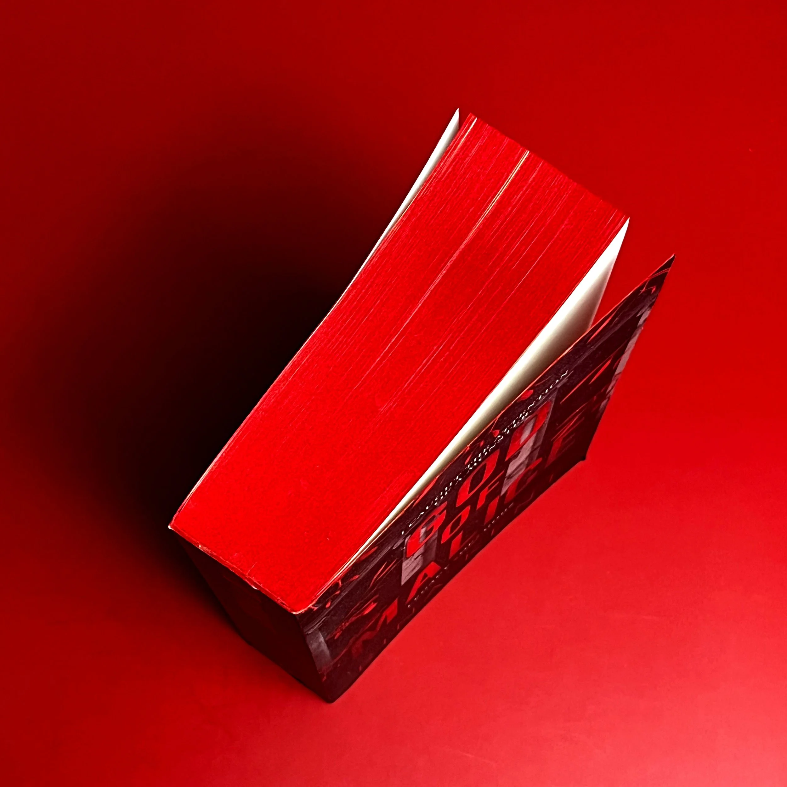 Above picture of book with red sprayed edges against red backdrop.