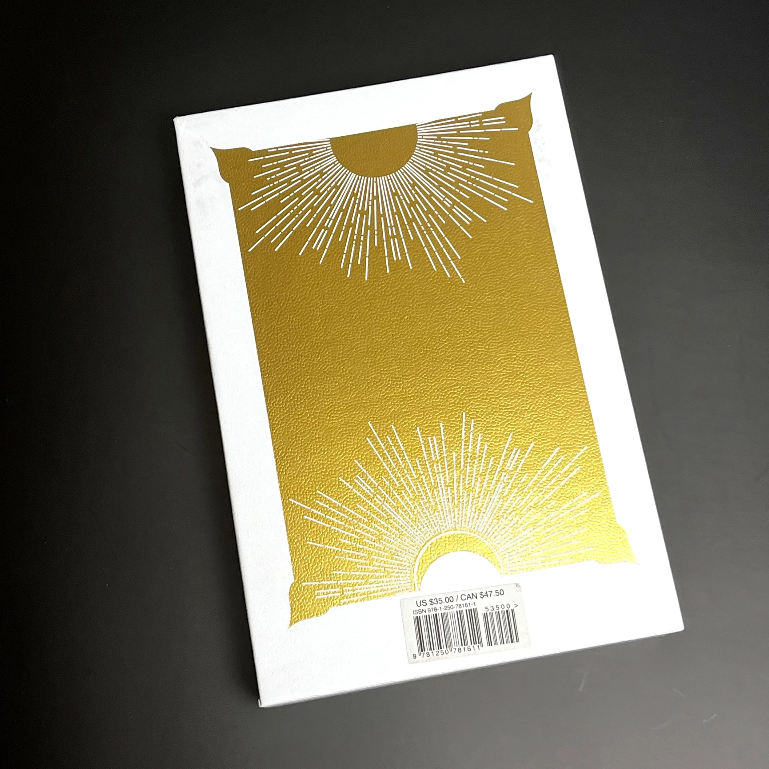 White hard shell cover with metallic gold finish depicting sun shapes.