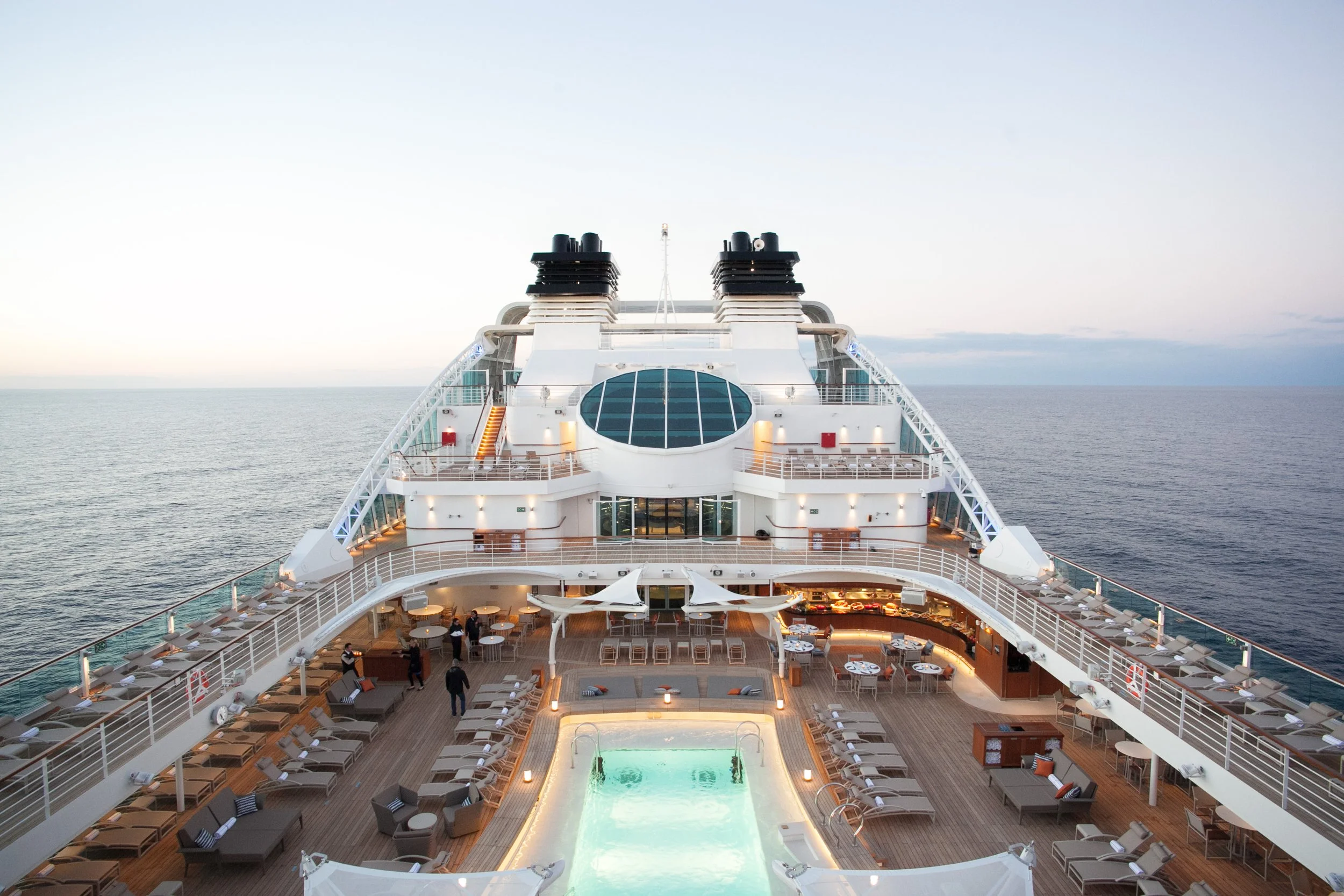Top view of the deck and pool area on a cruise ship at sea during sunset.