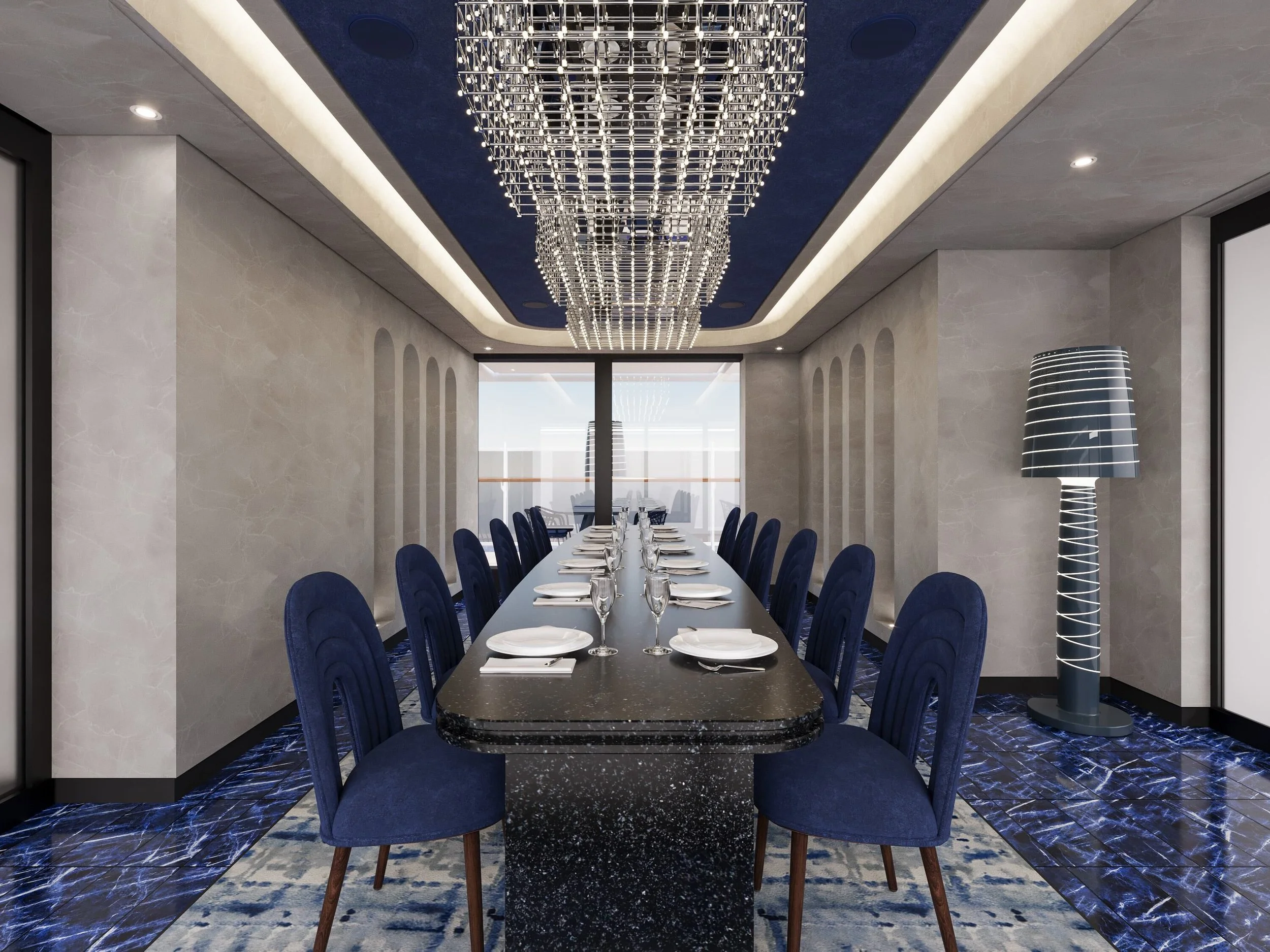 A modern dining room with a long black marble table set with white plates and wine glasses. Blue velvet chairs surround the table. A large crystal chandelier hangs from a blue ceiling. Gray walls and a floor lamp with black and white stripes are visible, with large windows at the far end showing an outdoor area.