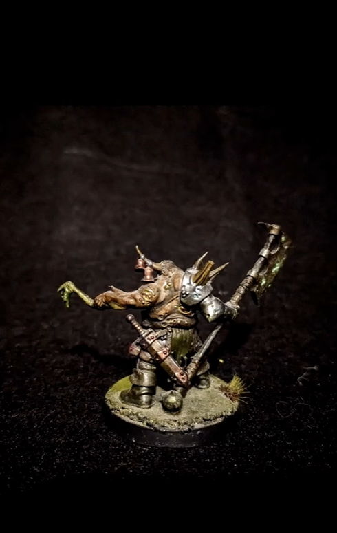 Miniature fantasy creature with horns, armor, and a large hammer, standing on a round base with grass.