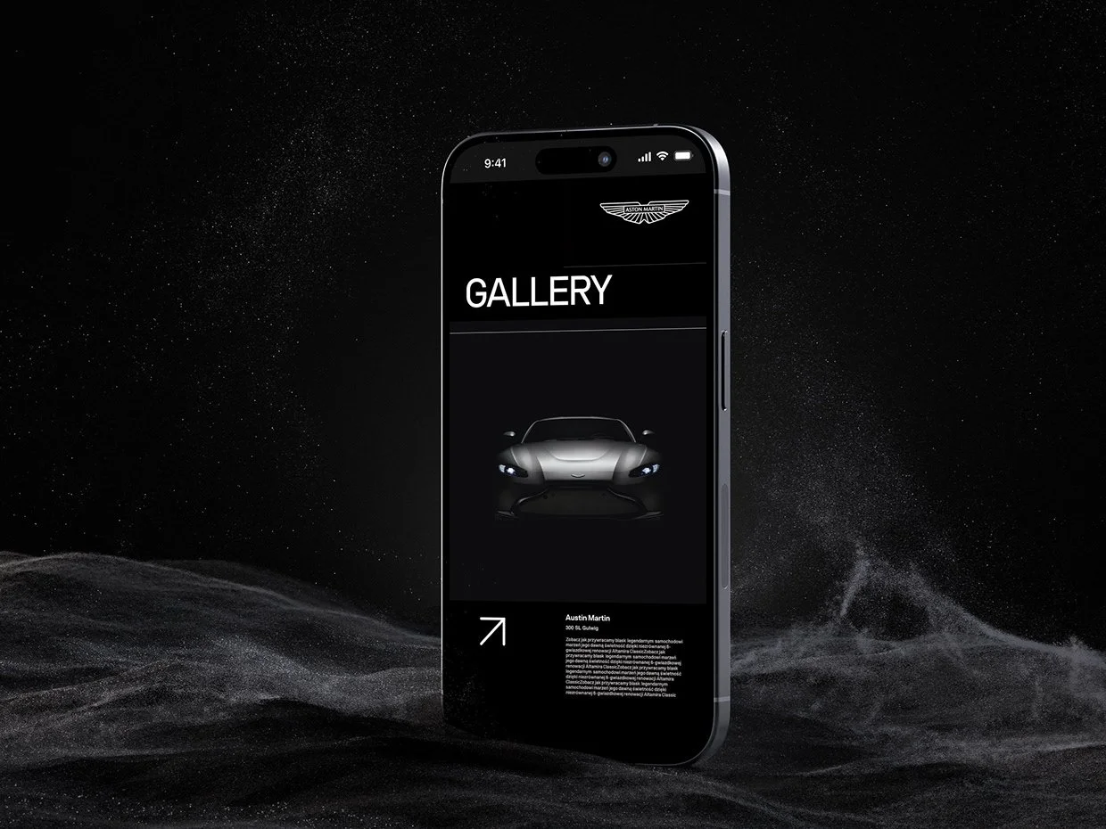 A smartphone displaying a car gallery app with an Aston Martin logo, a photo of a silver sports car, and some text, set against a dark, starry background with a textured surface.