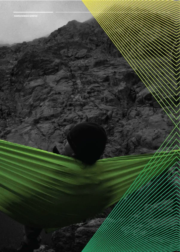 Person with a black hat holding a green blanket or cloth in a rocky outdoor landscape.