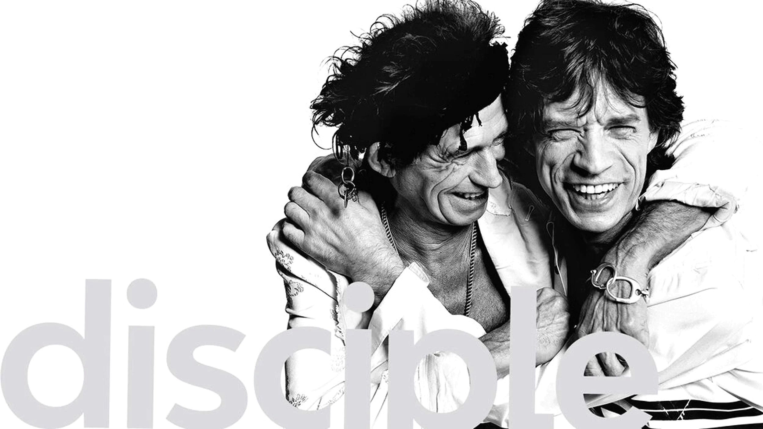 Black and white photo of two people embracing and smiling, one with an earring and the other with glasses and curly hair, showing happiness and friendship.