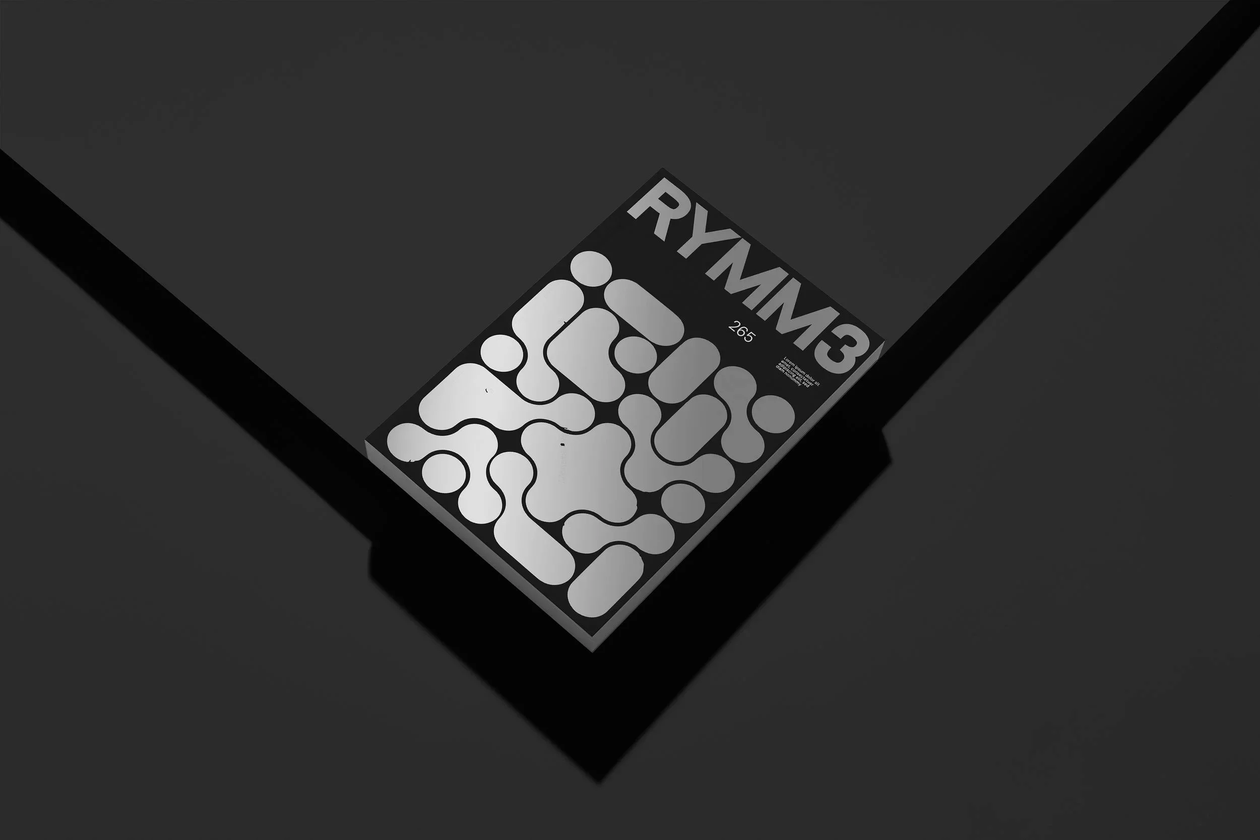 A black rectangular object with a sticker that says RYMAN 3 and 265, featuring a pattern of abstract connected shapes in black and white.