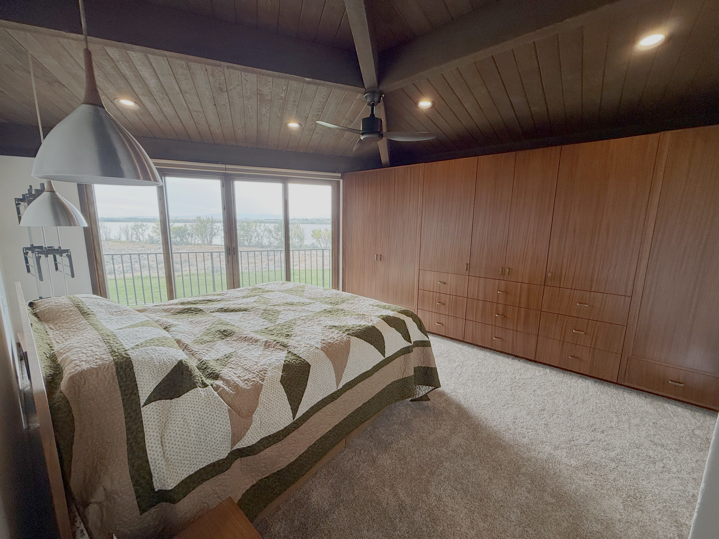 View of large wooden wardrobe with multiple doors and drawers in a carpeted room.