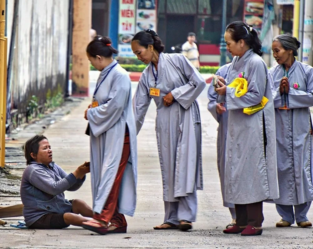 Vietnamese Buddhist volunteers distribute aid to a person on the street