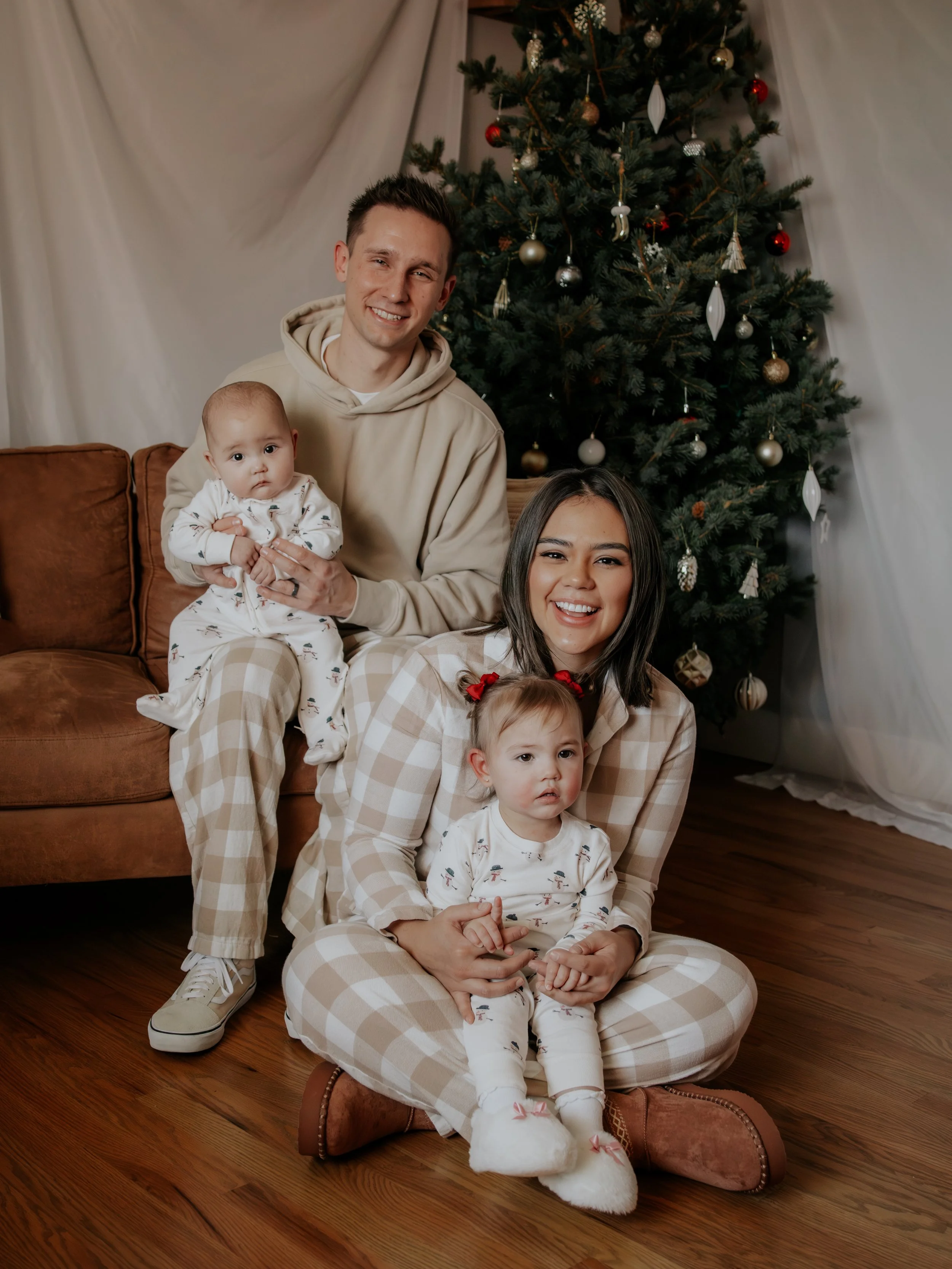 A husband and wife with their two children wearing pajamas for their Christmas photos taken by Kiela Rain Photography