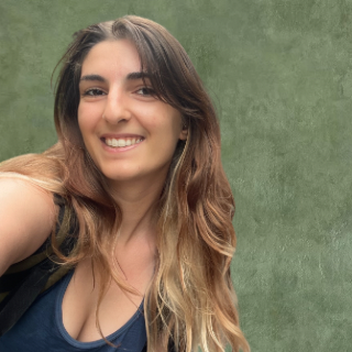 Portrait d'une jeune femme brune souriante, qui inspire bienveillance et gentillesse contre un fond vert.