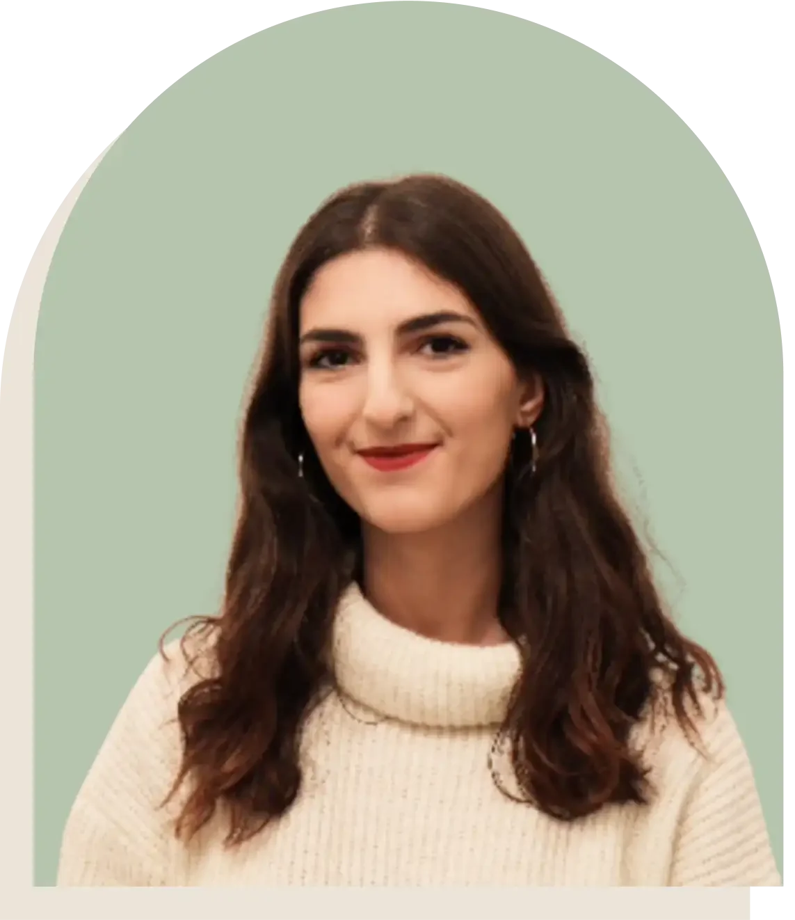 Portrait d'une femme souriante avec cheveux longs bruns, portant un pull beige à col roulé, contre un fond vert pâle.