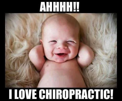 A happy baby lying on a fluffy blanket with hands behind its head, smiling wide, with text saying 'AHHHH!! I LOVE CHIROPRACTIC!'