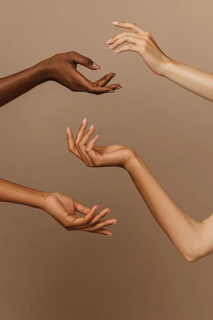 Four hands of different skin tones reaching out towards each other against a beige background.