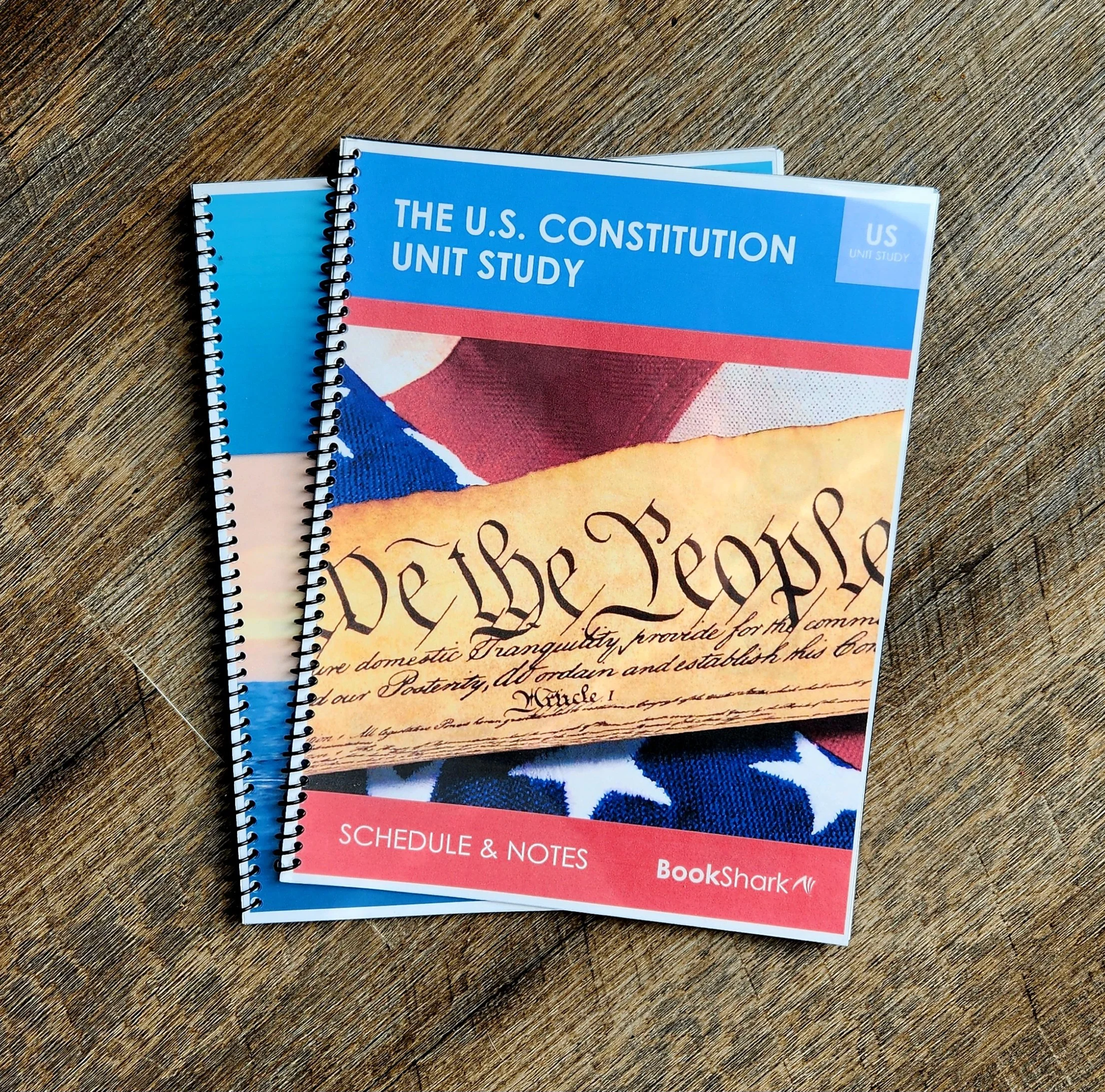 Two spiral-bound notebooks on a wooden surface, one on top of the other, with the top notebook titled 'The U.S. Constitution Unit Study'.