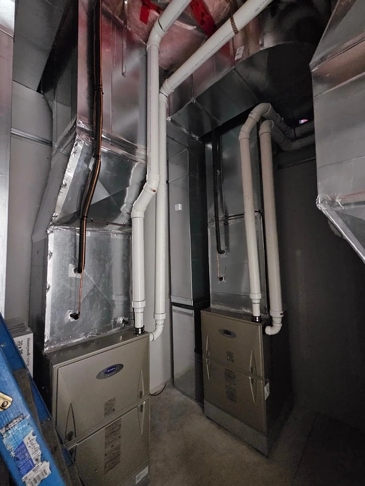 View of HVAC system ducts, pipes, and air handlers in a mechanical room.