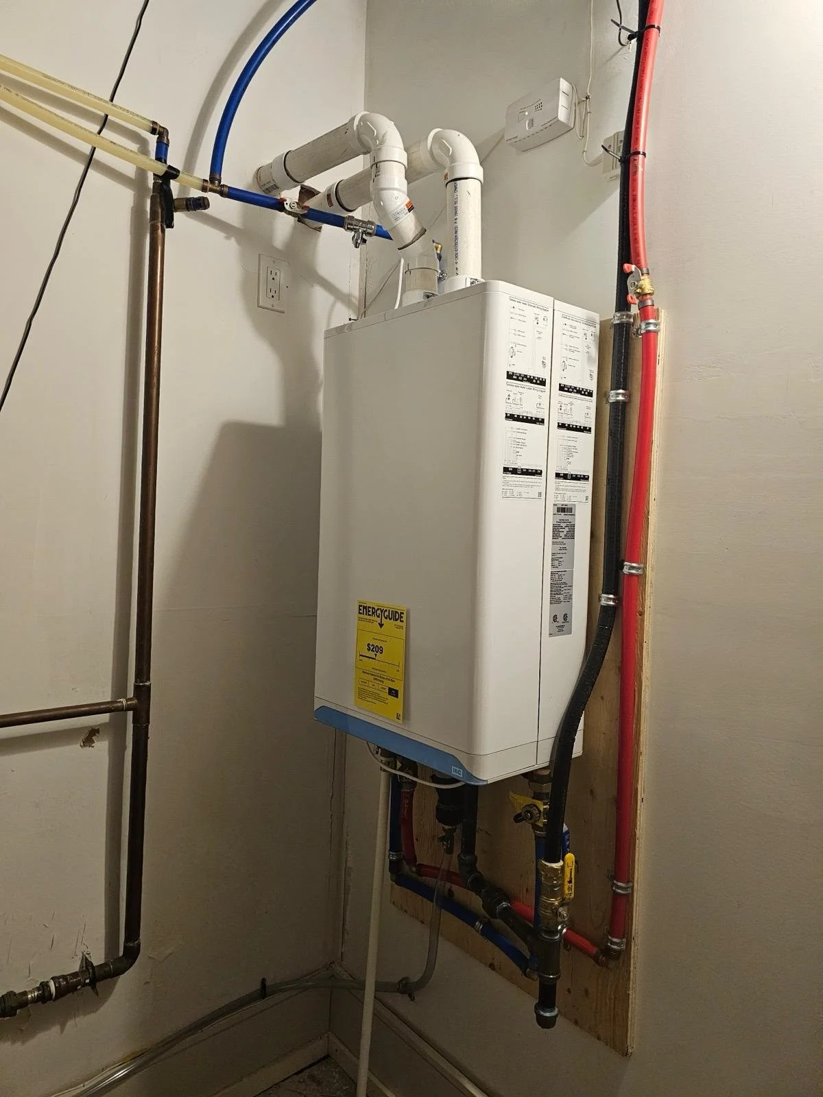 A water heater and plumbing pipes in a utility room.