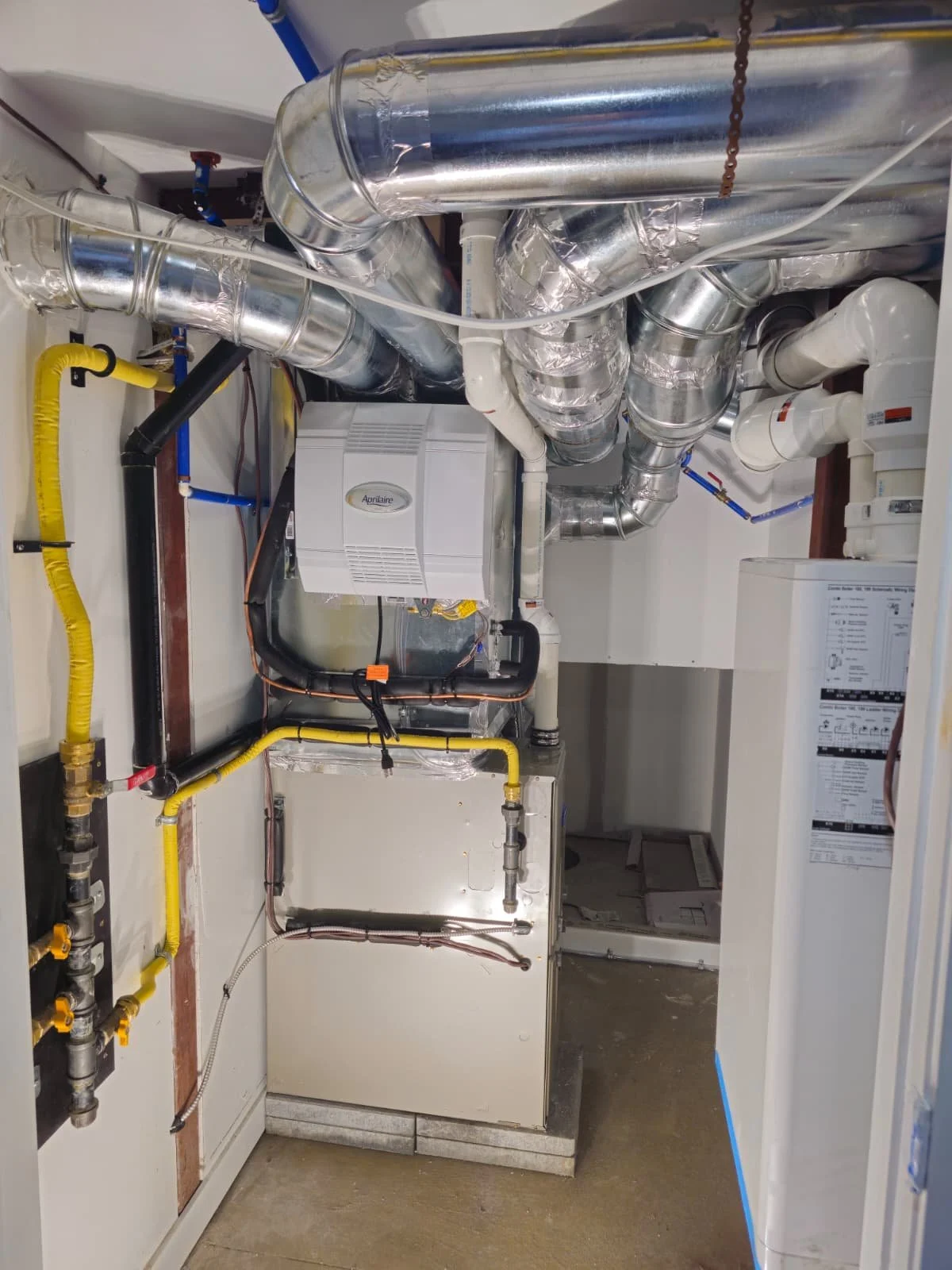 Mechanical room with ductwork, pipes, and HVAC equipment.