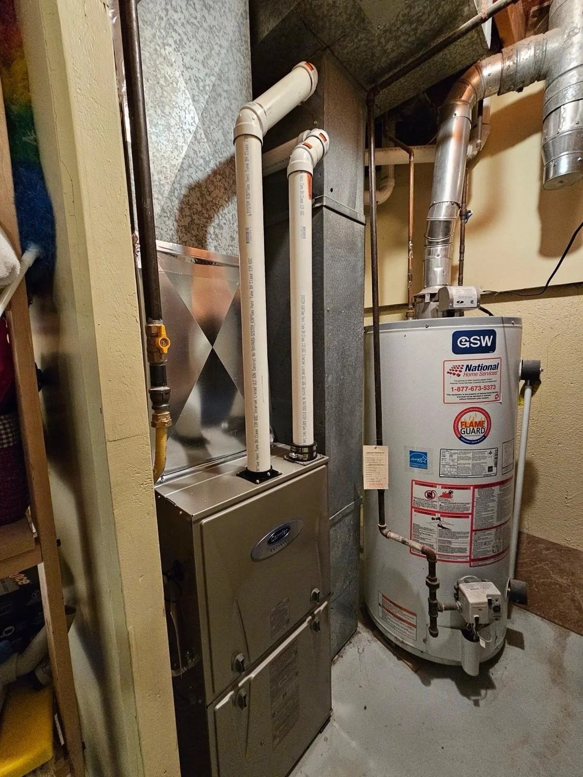 A utility closet with a water heater labeled GSW and a furnace with white PVC pipes connected.