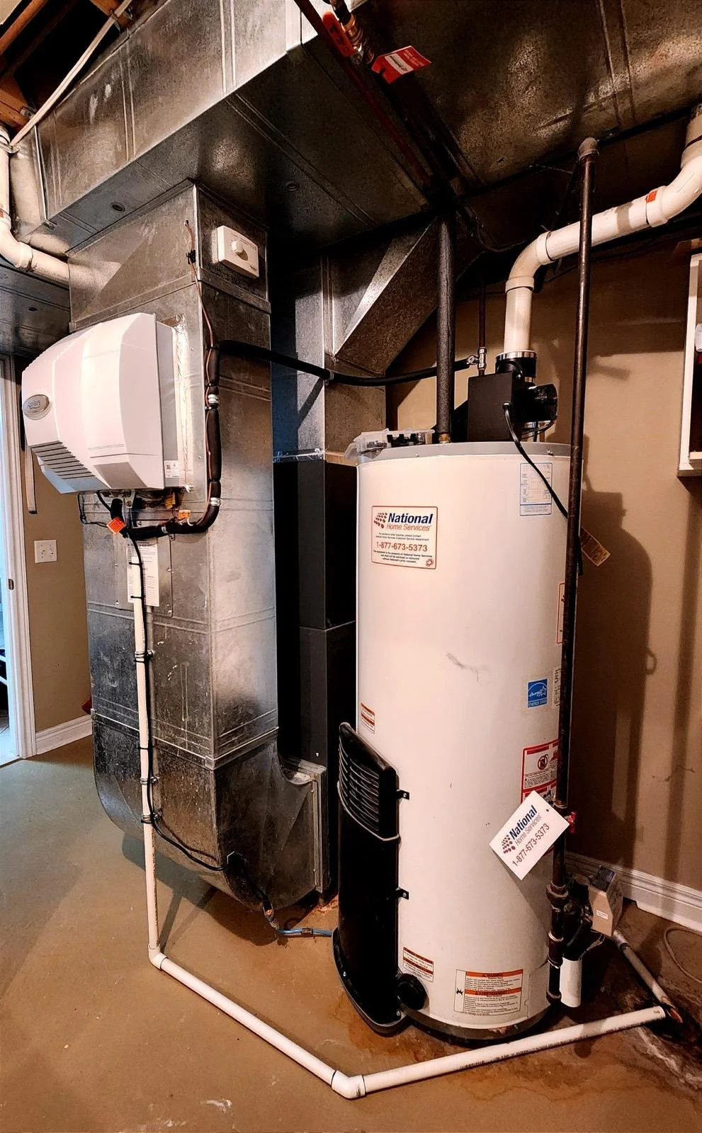 A utility room with a white water heater, an electric tankless water heater, and ducting.
