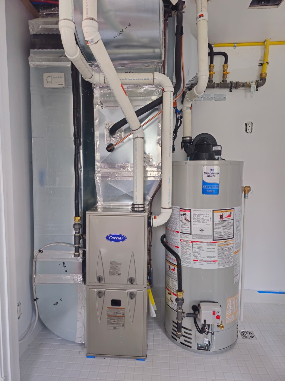 A water heater and HVAC system with pipes, ducts, and control panels in a utility room.