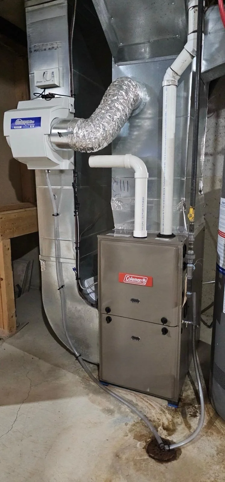 An HVAC system with ductwork, a Coleman furnace, and a nearby water heater in a basement.