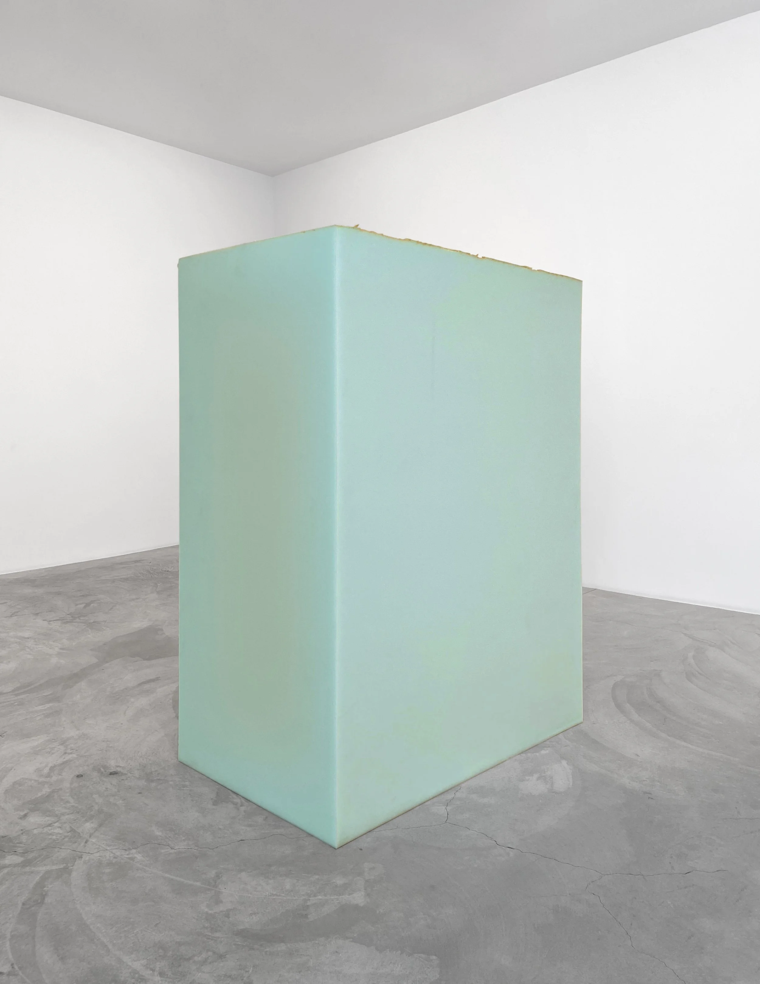 A large block of light, turquoise-colored foam. The block is in the shape of a large rectangle, with the long sides of the rectangle positioned vertically. The foam has some slight discoloration to it, mainly some occasional yellow streaks.