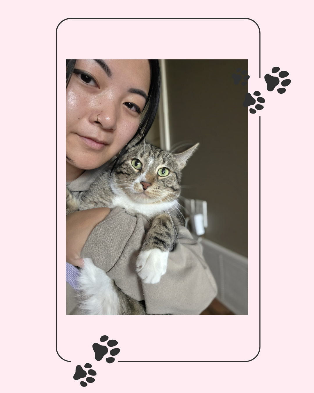 Person holding a tabby cat with green eyes, both looking at the camera.