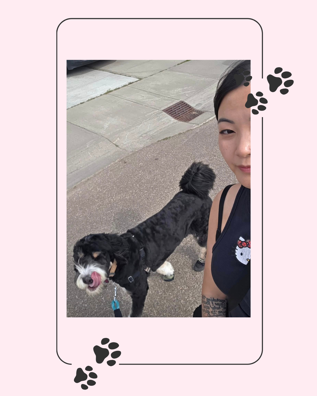 A woman taking a selfie with her dog on a sidewalk, with both looking relaxed and the woman smiling slightly, wearing a sleeveless top with a Hello Kitty logo.