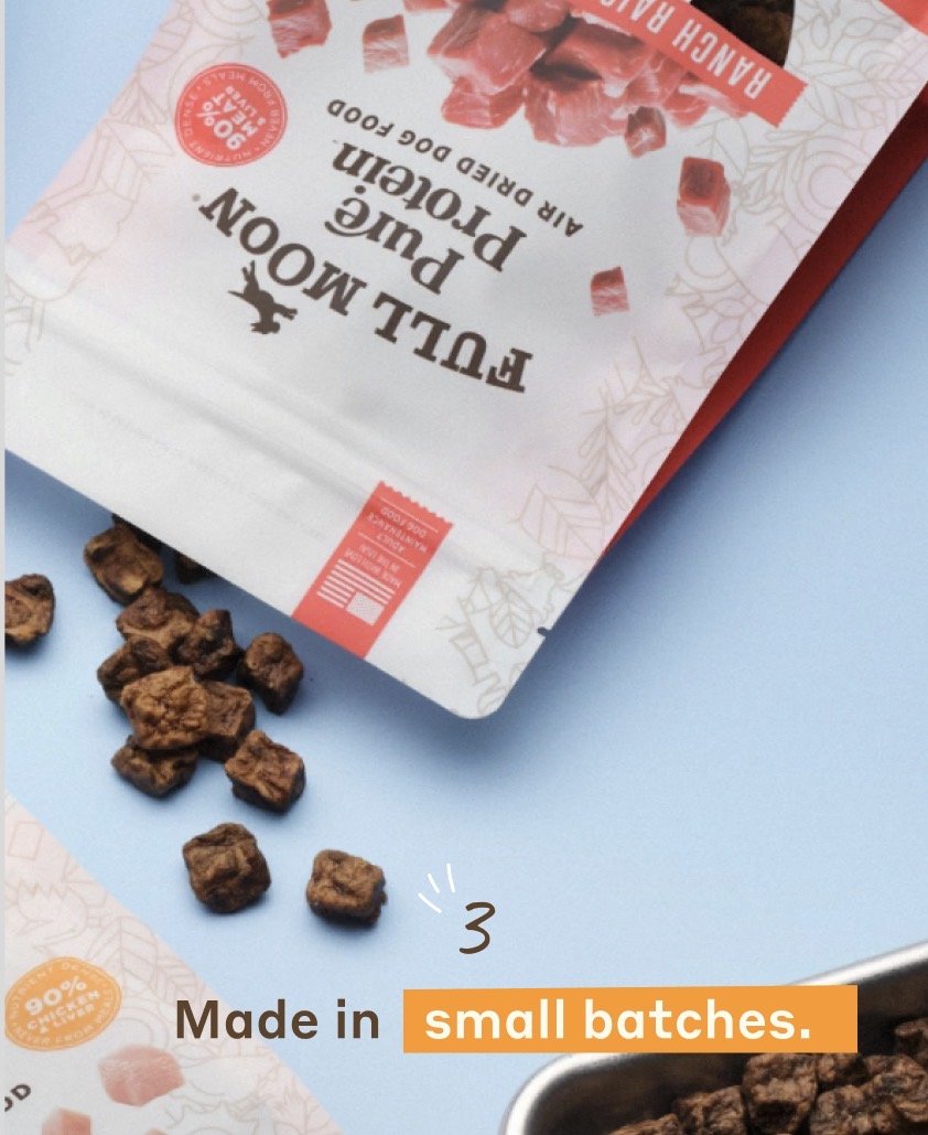 A partially opened box of Füll Mön Chien pink pudding dessert mix with small chocolate chunks spilled on a blue surface. Text overlays indicate the product is made in small batches.