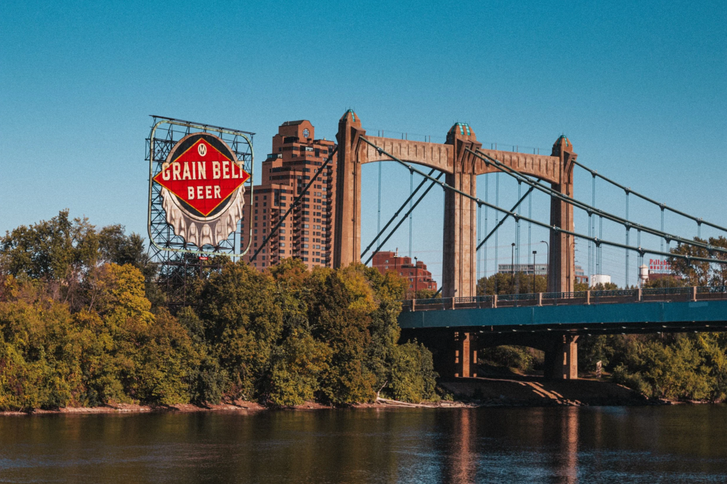 Hennepin Bridge over the Mississippi River with a city skyline in the background and a Grain Belt Beer billboard on the left.