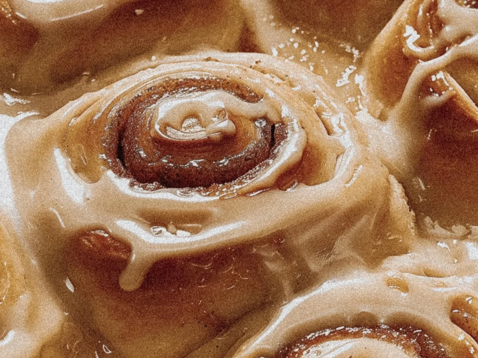 Close-up of several cinnamon rolls with icing.