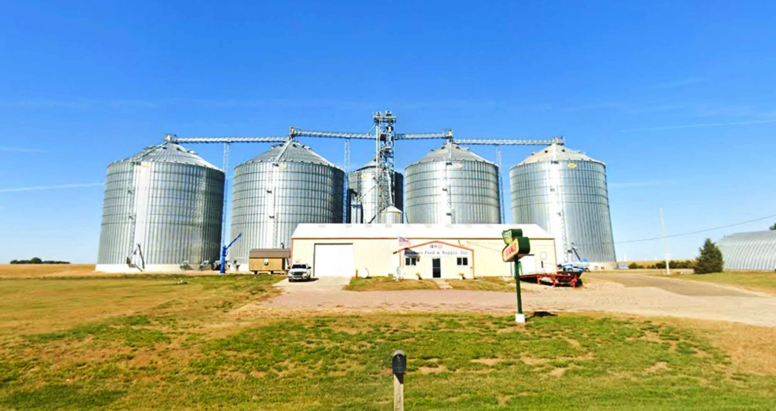 Paullina location with four large metal silos under a clear blue sky.