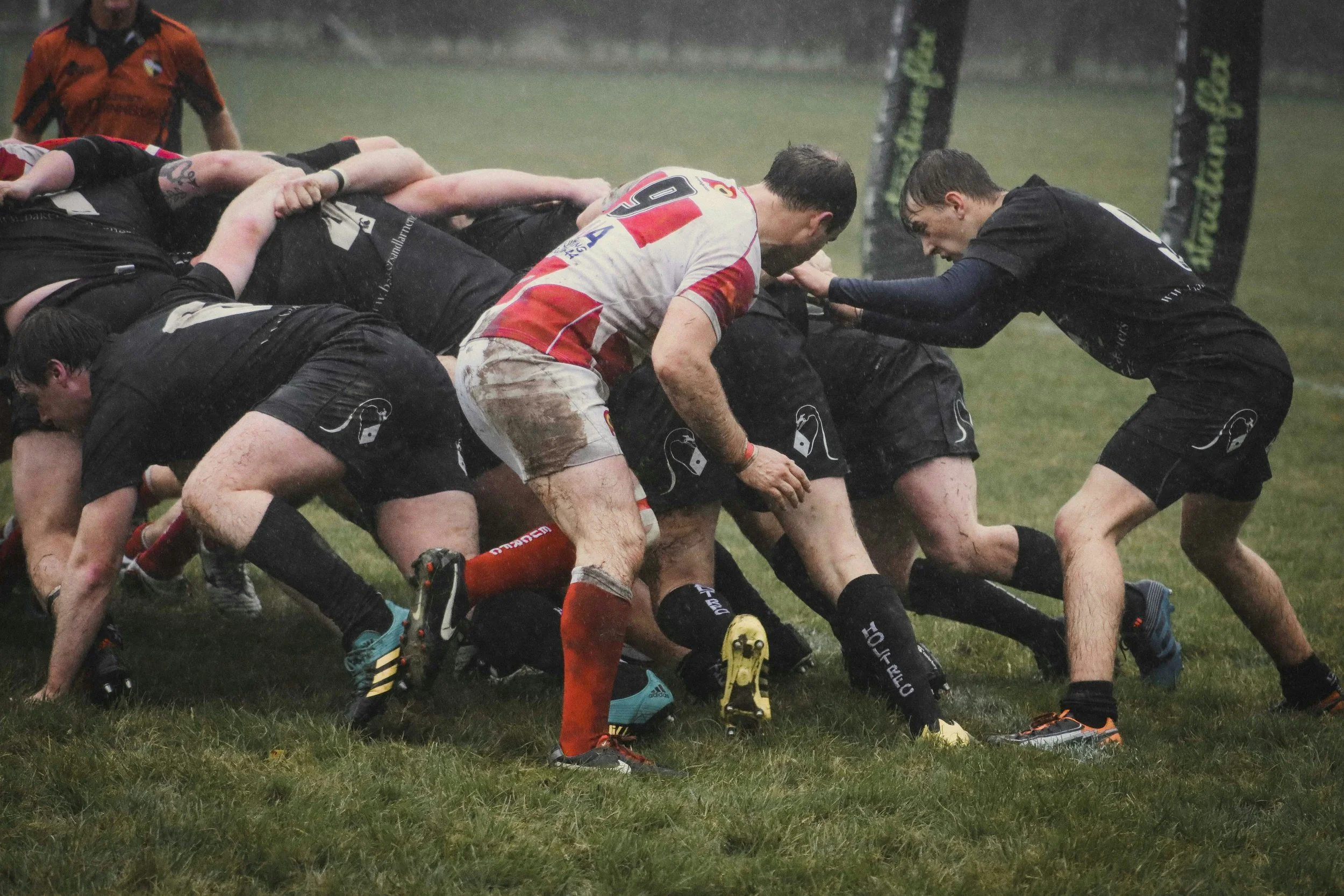 Rugby players engaged in a scrum on a rainy field during a match.