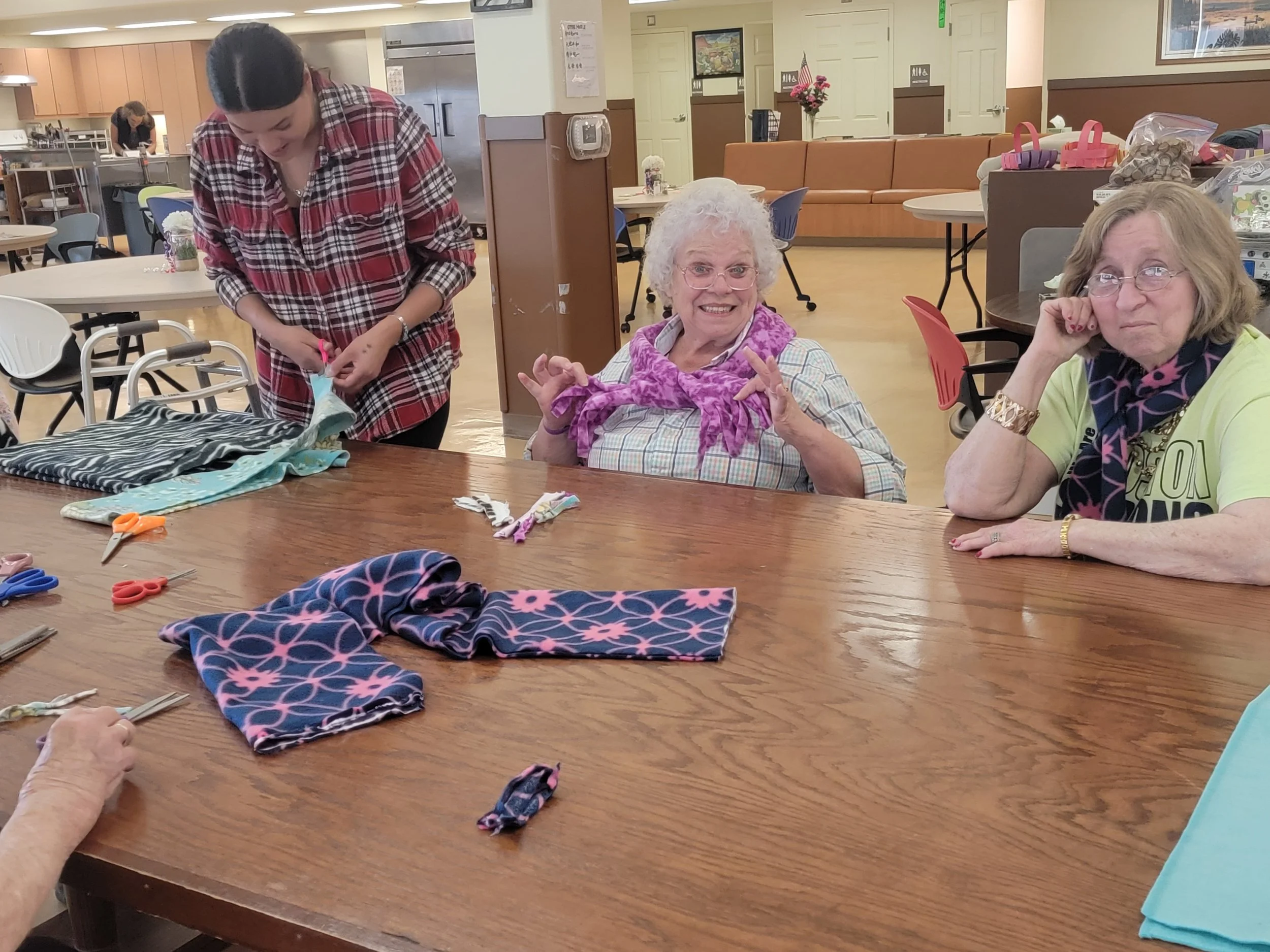 MatSu Senior Center Adult Day Services working with sewing supplies and fabric on the table.