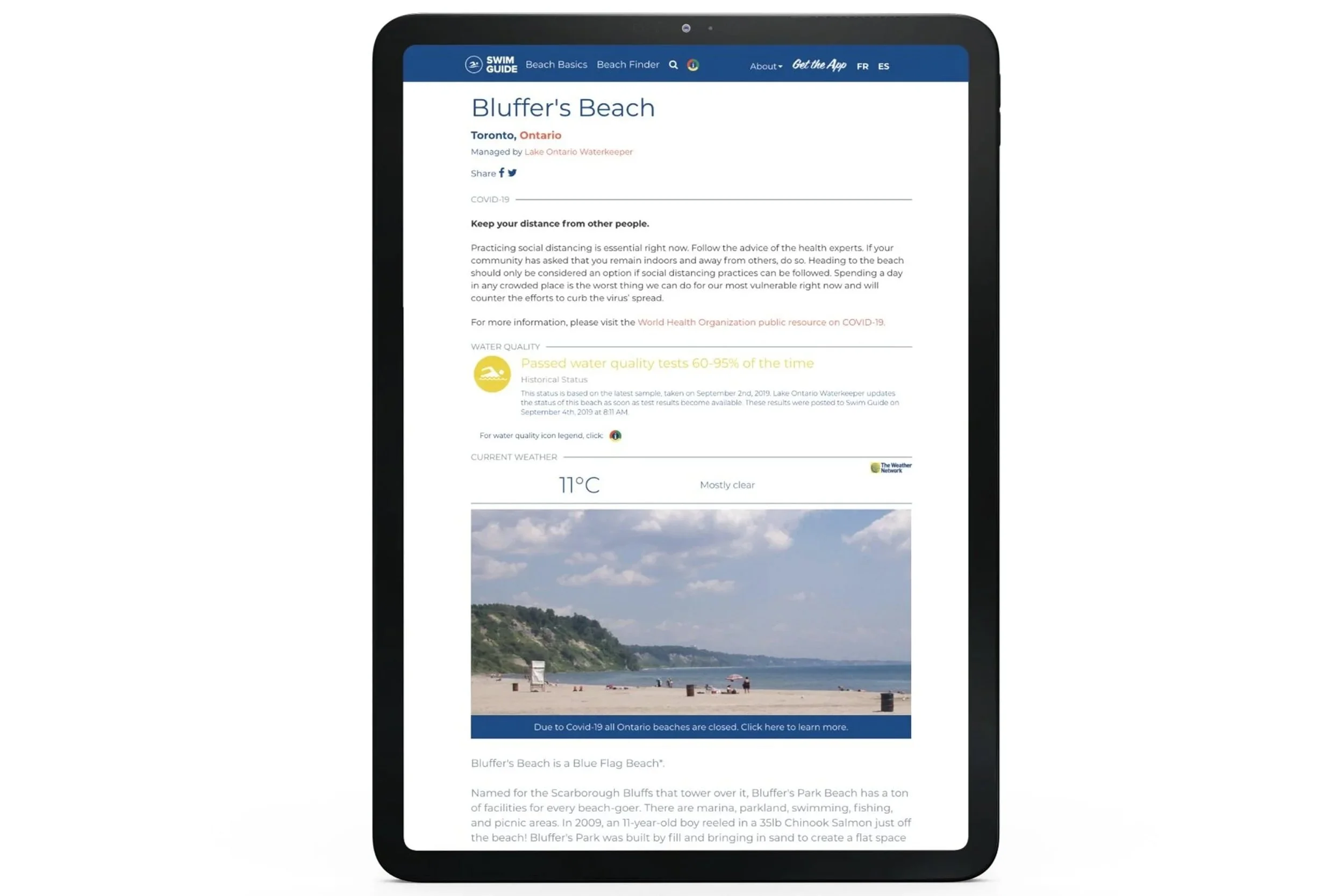 A tablet displaying a webpage about Bluffer's Beach in Toronto, Ontario. The webpage shows the water quality status, current weather at 11°C and mostly clear skies, and a photo of the beach with sand, umbrellas, and people enjoying the day.