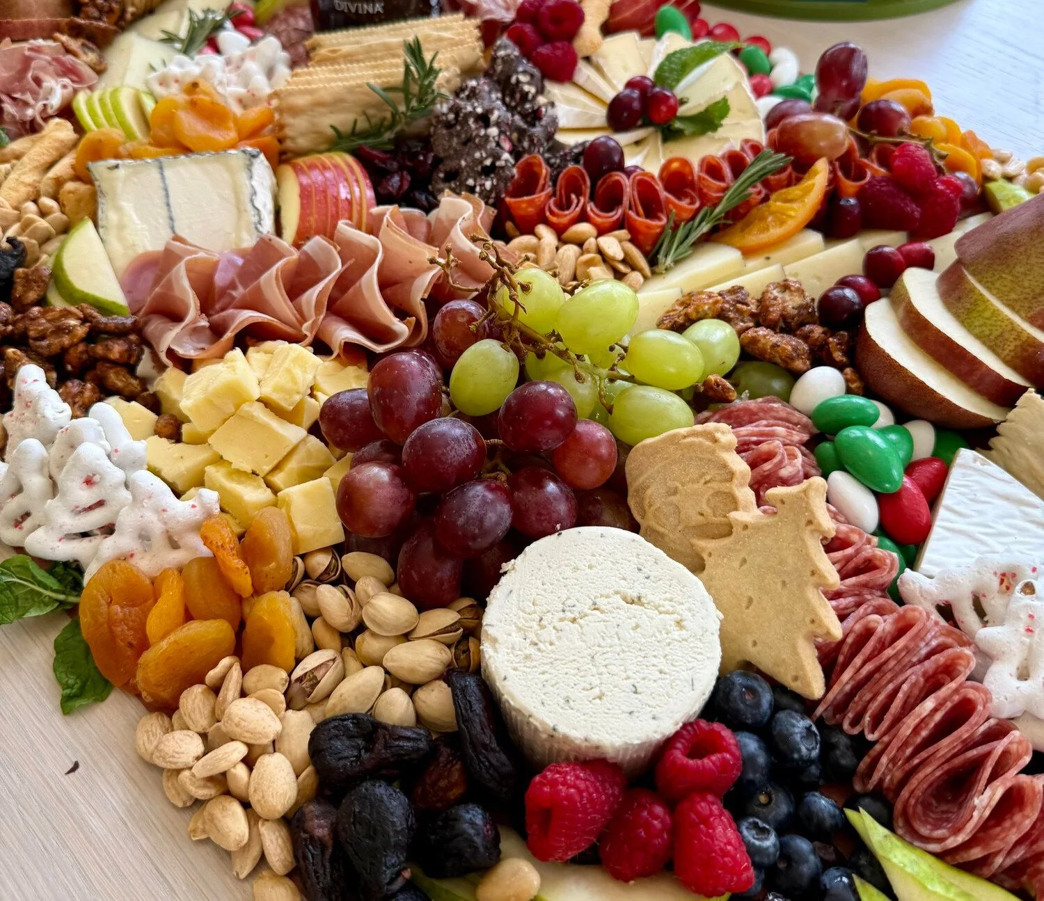 Assorted cheese, grapes, crackers, dried fruits, nuts, berries, and cured meats on a charcuterie board.