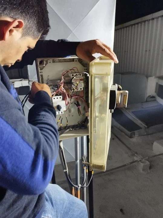 Persona reparando un aparato electrónico con componentes internos expuestos.
