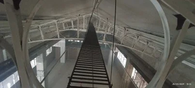 Escalera de acceso en un espacio interior con ventanas y estructura metálica.