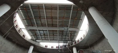 Vista del interior de un estacionamiento subterráneo, mostrando un techo con estructura metálica y columnas de soporte.