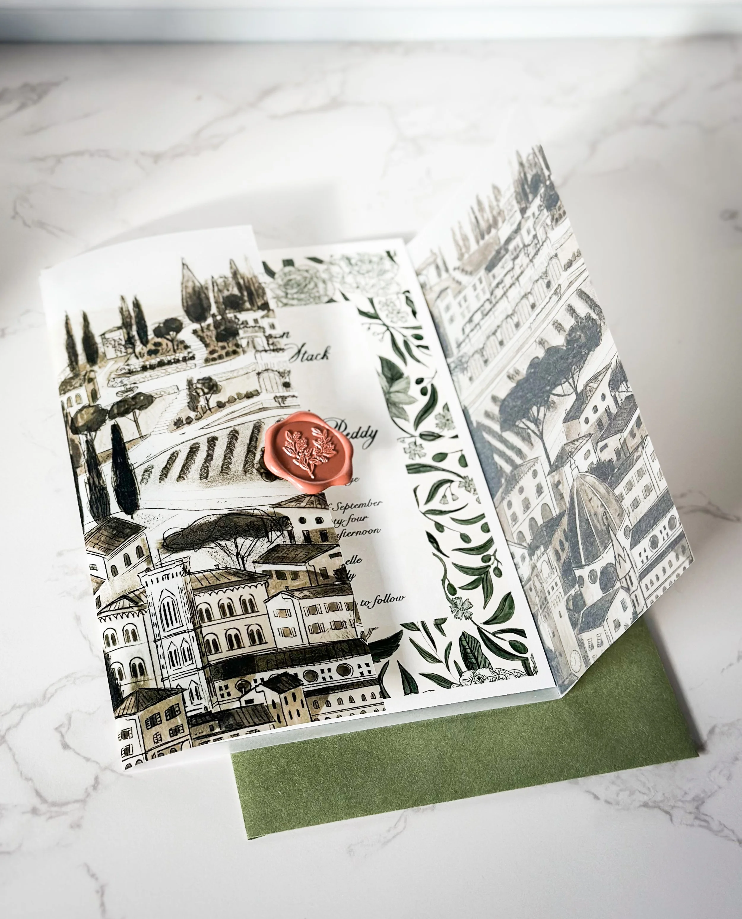 Folded vellum with a custom illustration of the Florence skyline for a wedding at Villa le Fontanelle in Tuscany, Italy. Sealed with a classic red wax seal, on white marble surface with a sage green envelope.