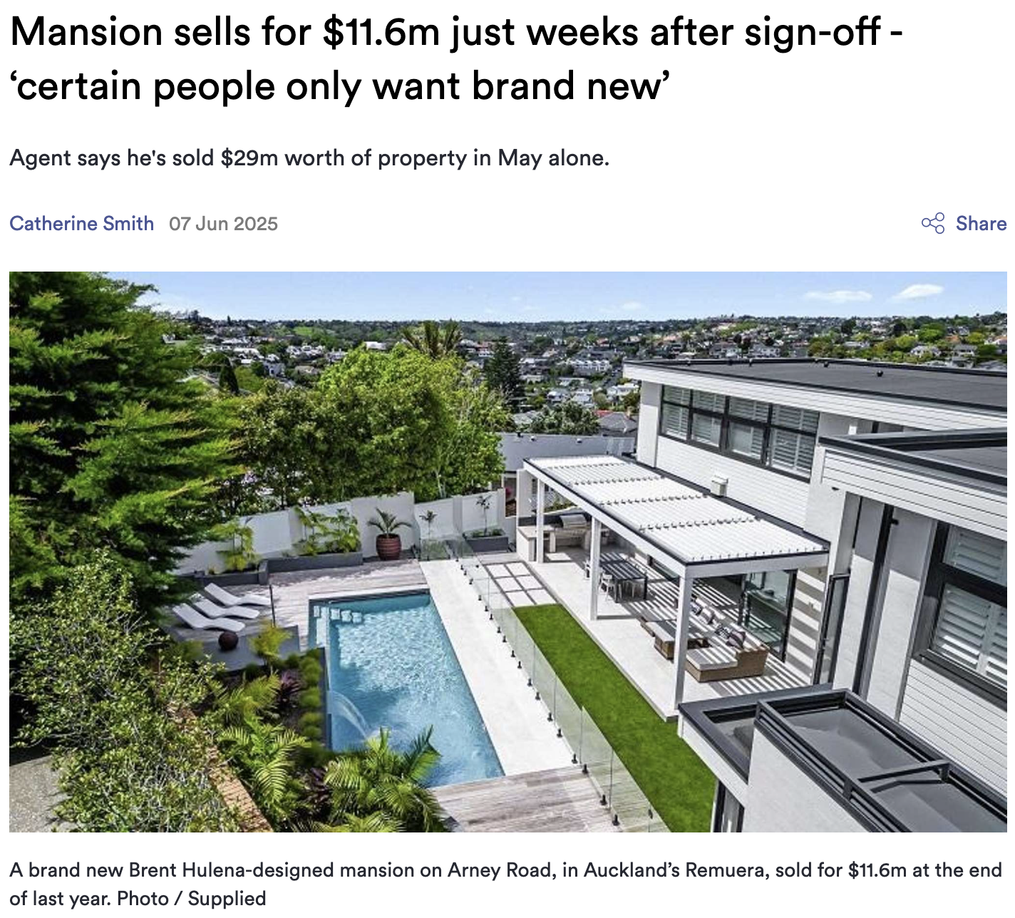 A modern white house with a backyard pool, sun loungers, and a covered patio area, surrounded by lush green trees and overlooking a cityscape of Auckland, New Zealand.