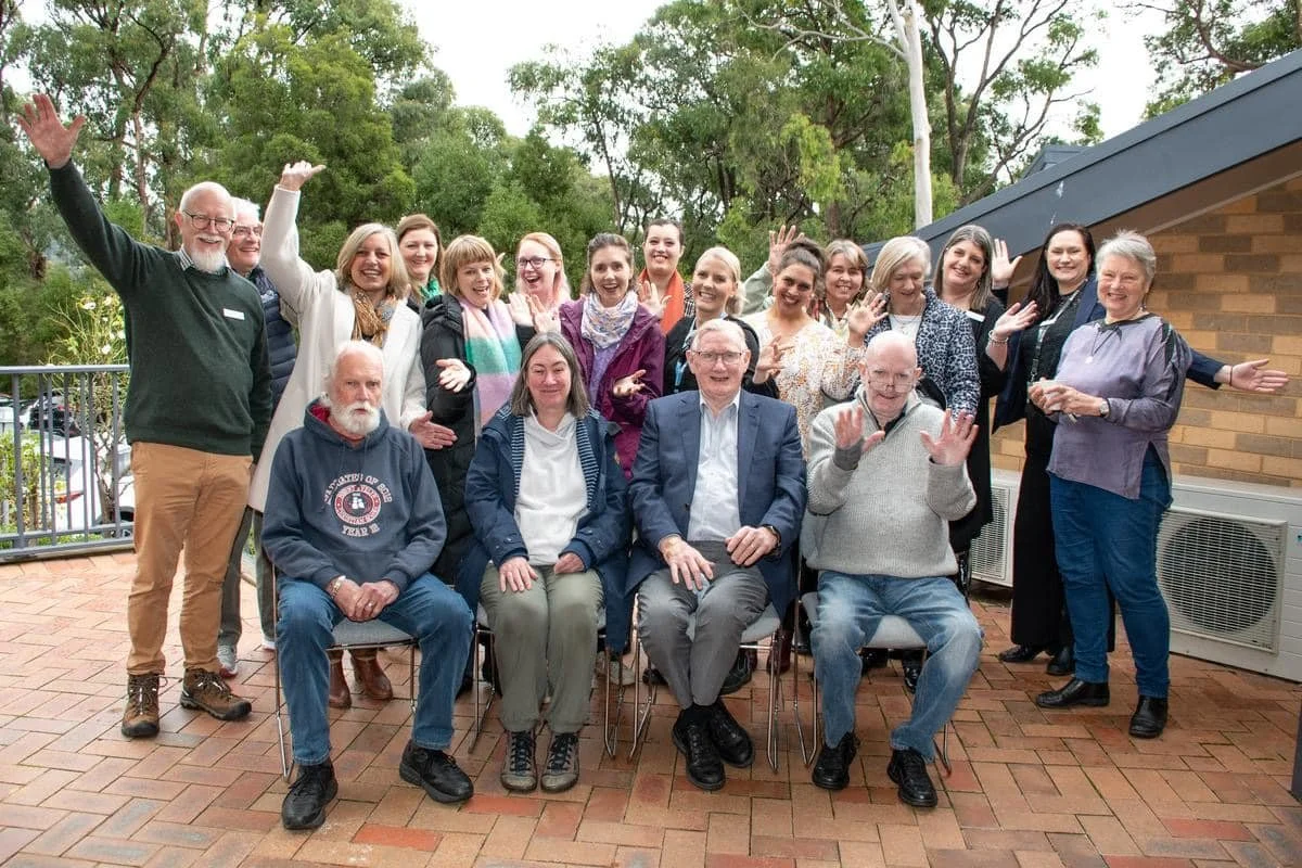 20 Alumni of varying ages clustered together for a group photo