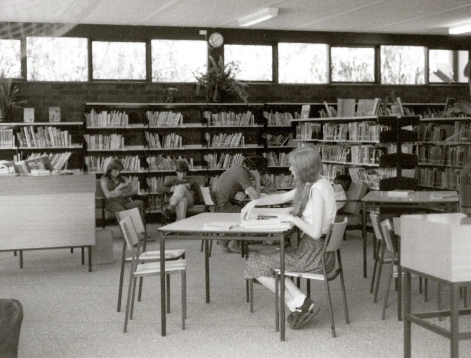 Vintage black and white photography of students scattered around a library