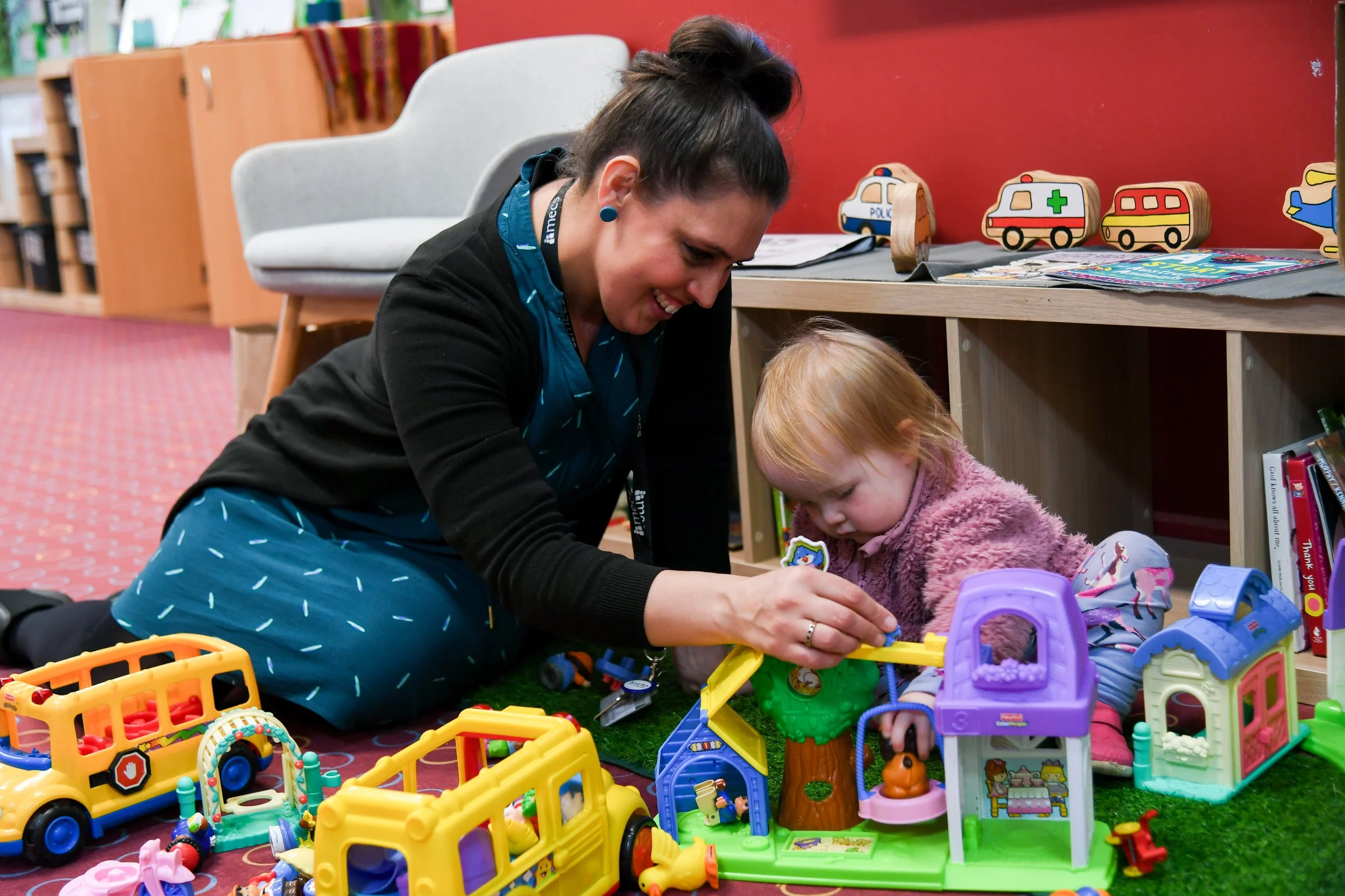 Playgroup facilitator plays on ground with a toddler