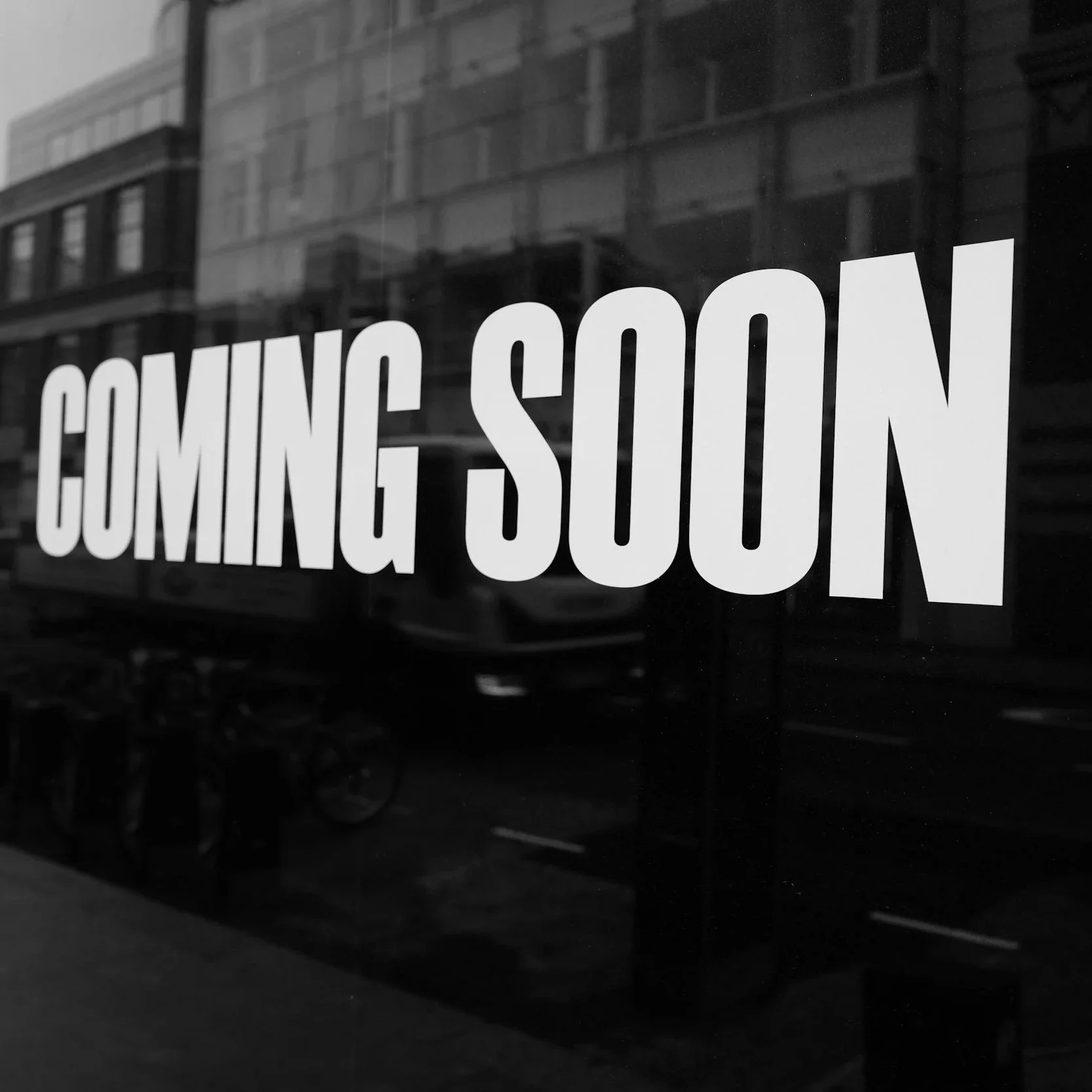 Black and white storefront window sign reading 'Coming Soon'