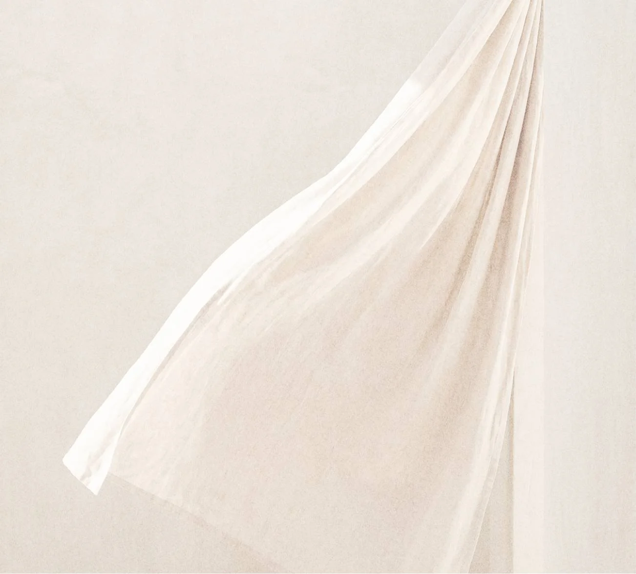 A close-up of a white and beige fabric with a textured pattern and diagonal folds.