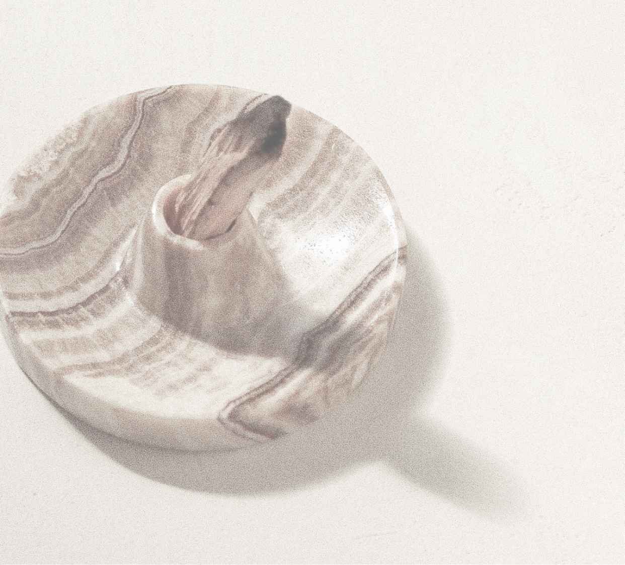 Marble ball with swirled gray and white pattern casting a shadow on a white background.
