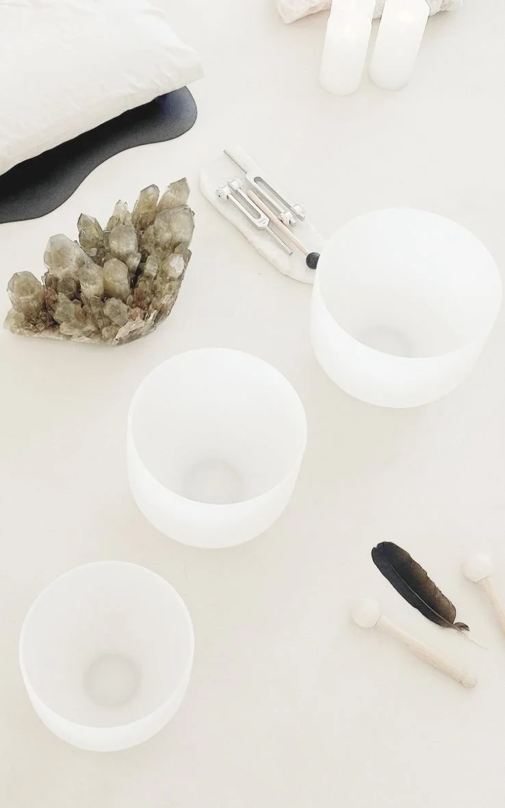 White table with three frosted glass candle holders, a crystal cluster, a black and white pillow, a small black and white sculpture, and a white feather with a black tip.