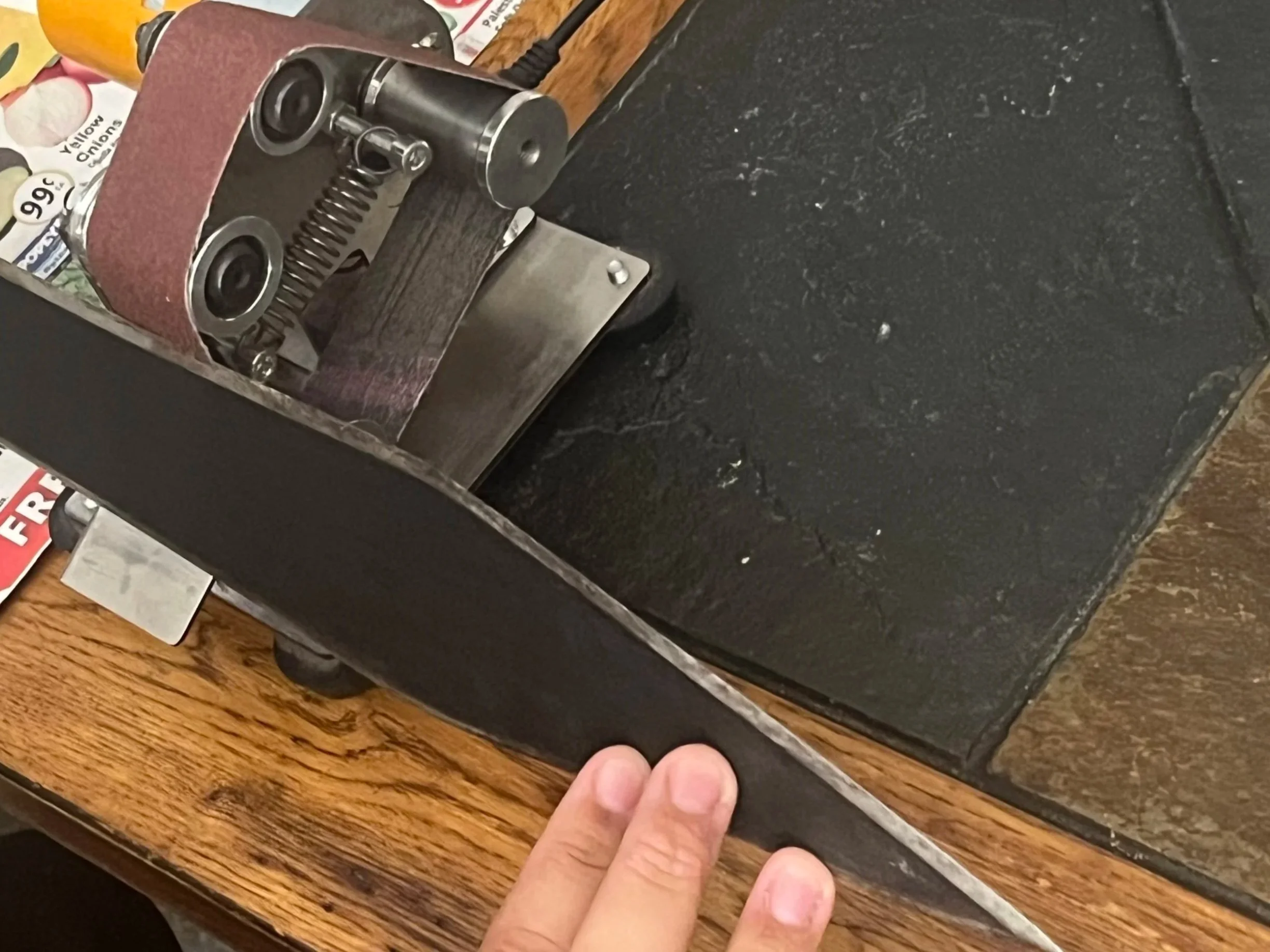 A hand pressing a black power button on a vintage black and silver slot machine with a wooden base, placed on a wooden table.