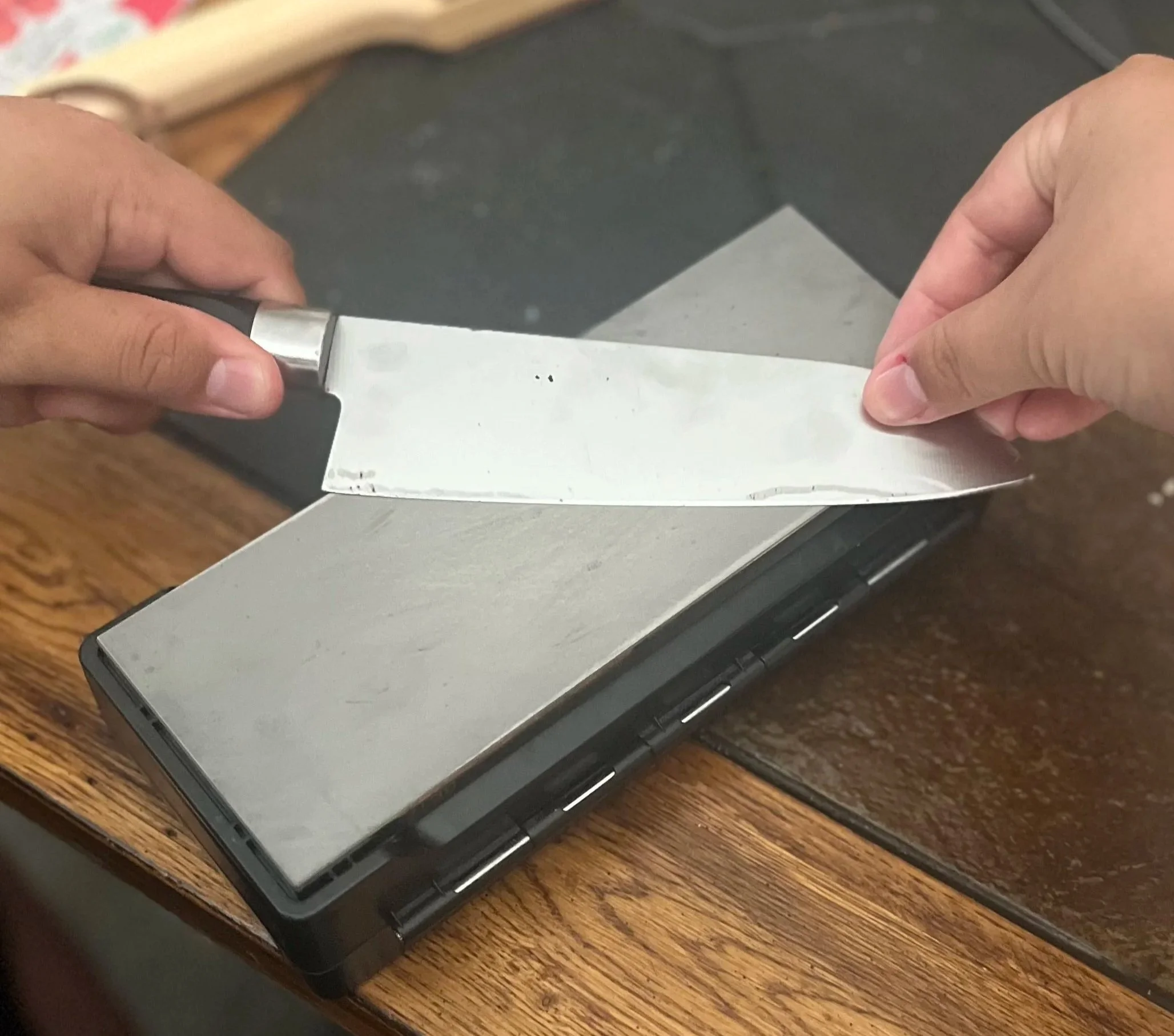 Person sharpening a knife on a diamond stone.